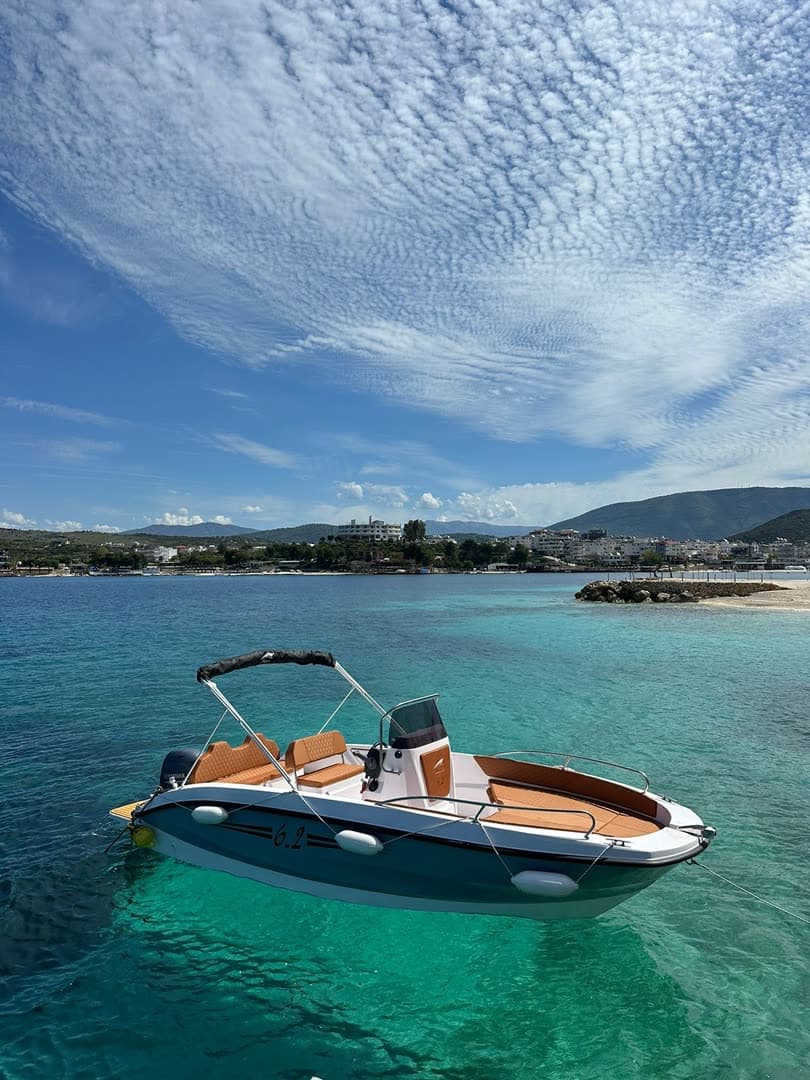 A console boat on glassy turquoise under a mackerel sky off Ksamil
