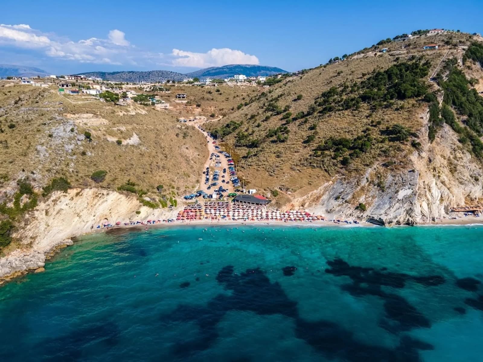 Pasqyra (Mirror Beach) · white-pebble cove under pale cliffs, mirror-flat turquoise water