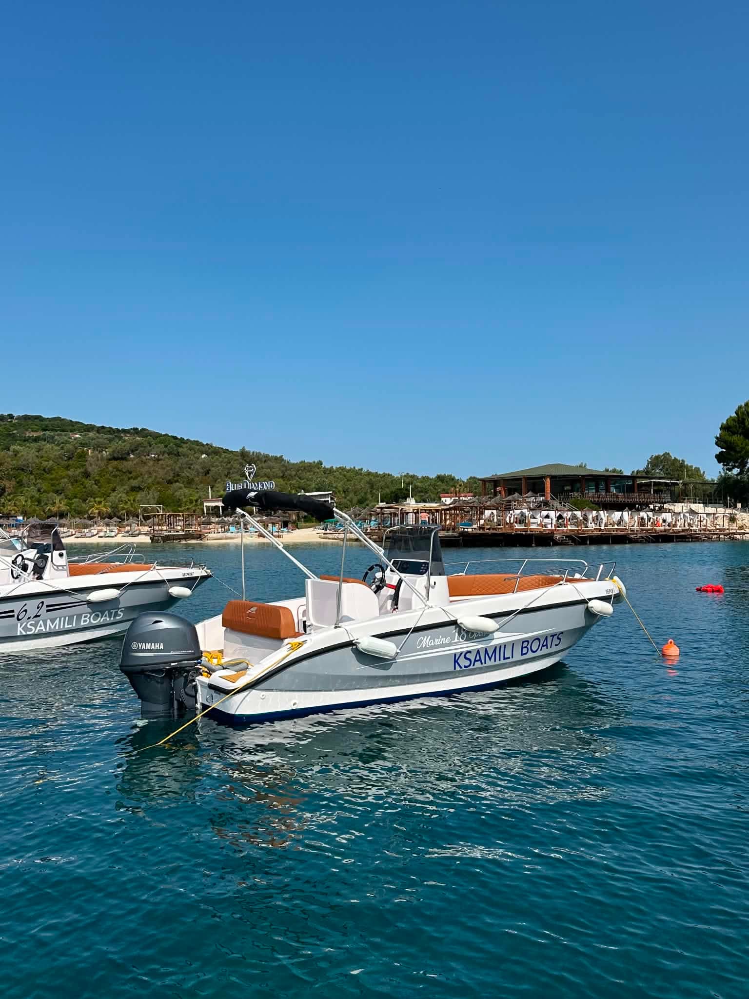 Two Ksamili Boats anchored side by side on bright turquoise water off the Ksamil beach